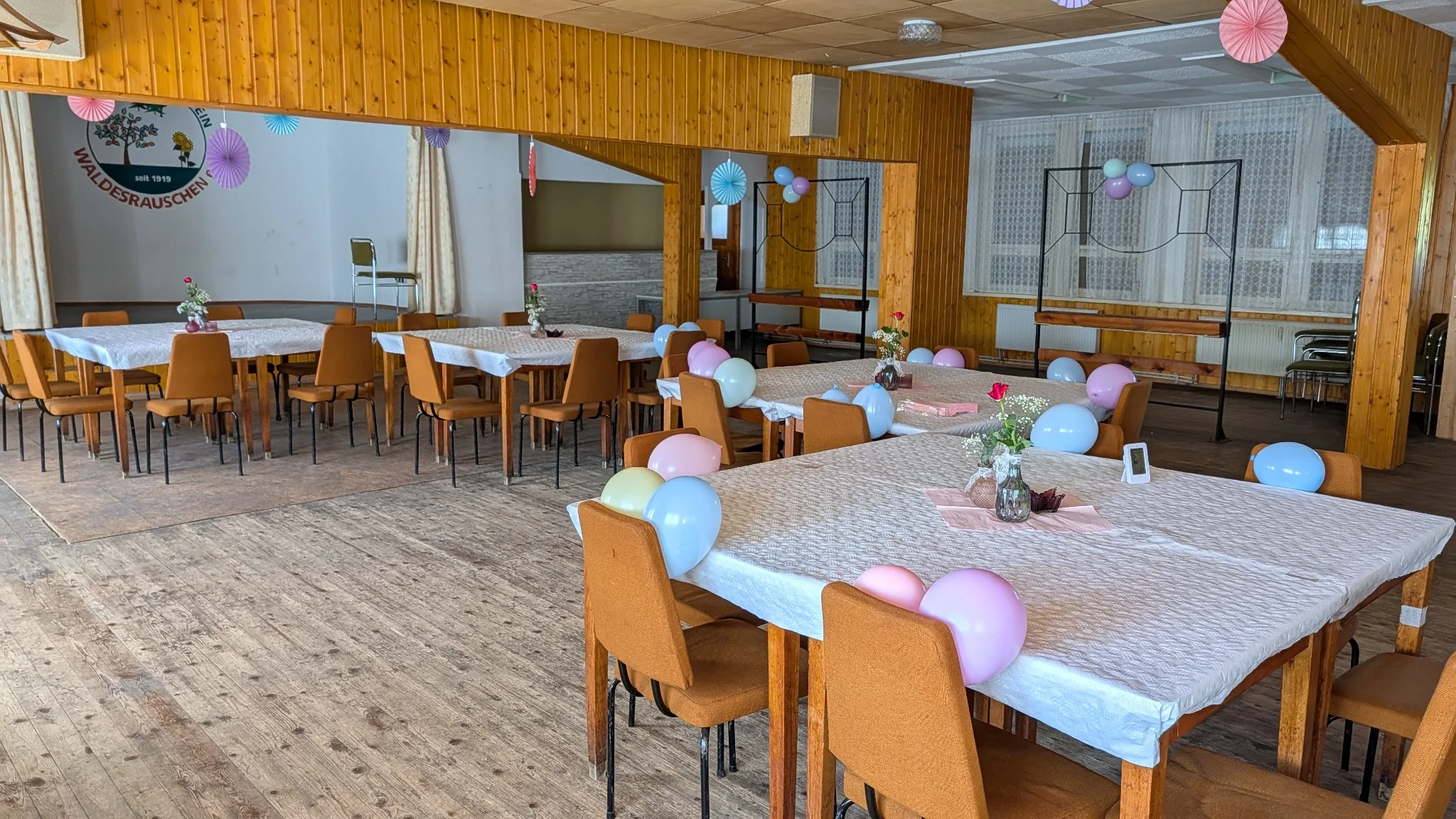 Festlich geschmückter Saal mit bunten Papierrosetten